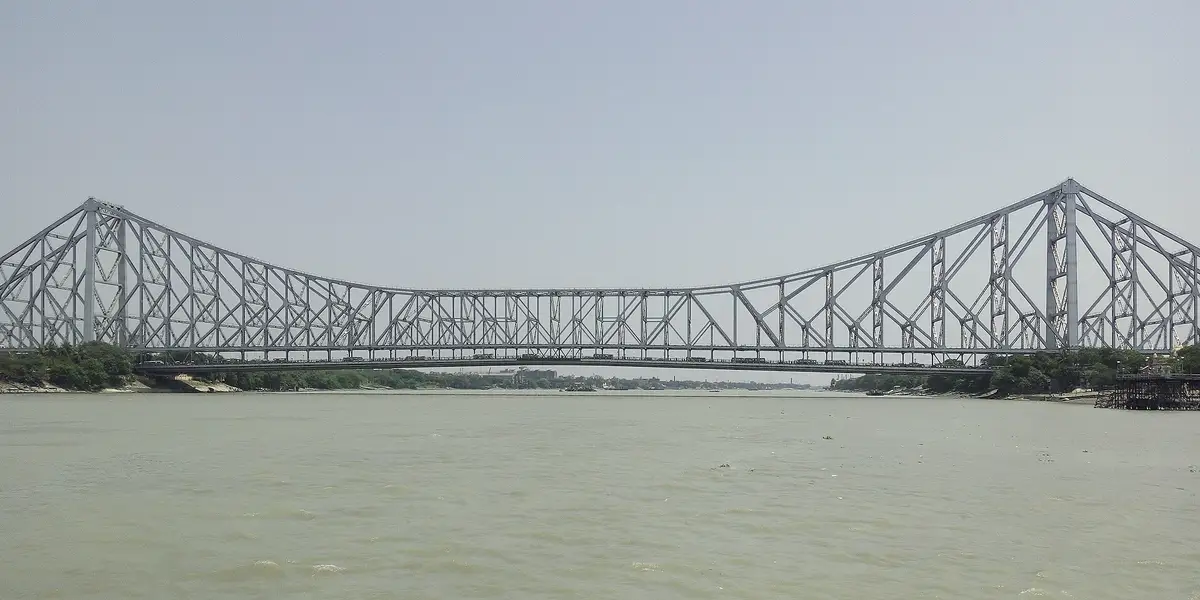Howrah Bridge spanning the Hooghly river in grey light.