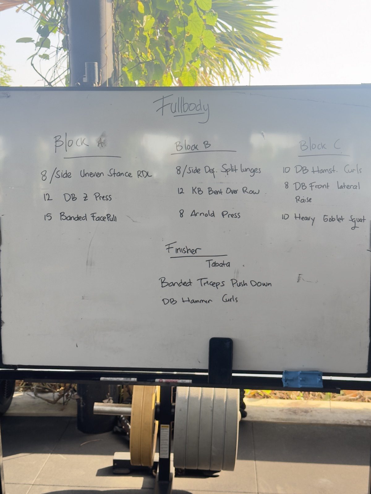 The whiteboard at Omni, Bali: a Fullbody workout in handwriting, split into Block A, Block B, Block C and a Tabata finisher, with plates stacked below